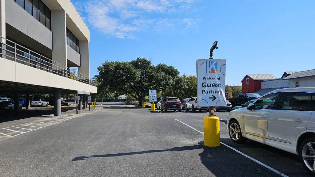 Guest Parking welcome sign with blue arrow pointing toward visitor parking